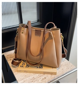 Close-up of beige lychee grain leather tote bag with brown handles and gold hardware
