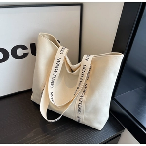 Detailed shot of cream canvas tote bag featuring branded black lettered woven handles