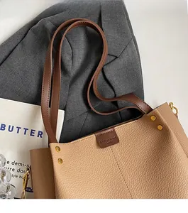 Close-up of light brown lychee grain leather tote bag with dark handles and gold rivets