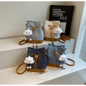 Detailed view of denim bucket bags with leather trim and plush cloud charms in four colors