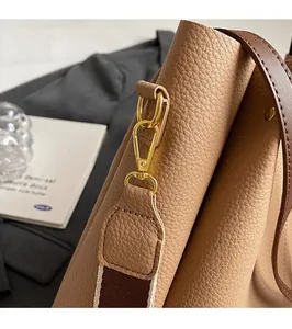 Detail of gold metal buckle and brown lychee grain leather with wide shoulder strap