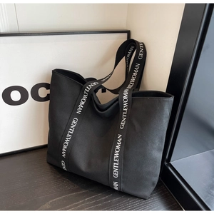 Close-up of black canvas tote bag with contrast logo strap and spacious interior