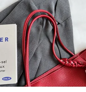 Detail of red lychee leather texture and woven satin side decoration on shoulder bag