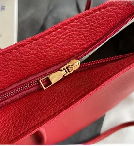 Detail of red lychee grain leather tote with a smooth golden metal zipper closure