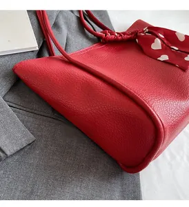 Detail of red pebbled PU leather tote bag with heart print scarf on top of a grey suit