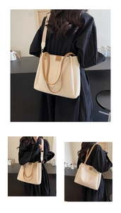Close-up of cream tote bag with litchi texture, brown leather label and wide shoulder strap
