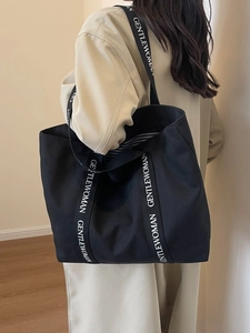 Minimalist black canvas tote bag with letter-printed straps for casual daily use