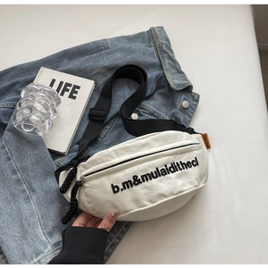Detailansicht weiße Nylon-Umhängetasche mit schwarzer Stickerei auf blauem Denim