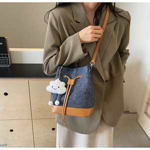 Denim and brown leather bucket bag featuring a drawstring closure and cute cloud charm