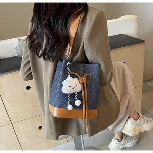 Detail of blue denim bucket bag with brown leather trim and cute white cloud charm
