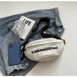 Detailansicht der weißen Nylon-Gürteltasche mit schwarzer Stickerei und Marken-Webetikett
