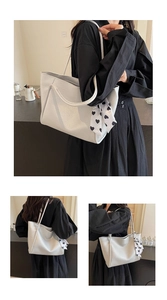Close-up of a white textured leather tote bag with a decorative heart pattern silk scarf