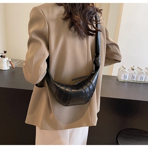 Close-up of a black pleated croissant bag with knotted strap worn by a model