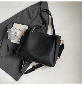 Detail of black pebbled leather tote bag with gold rivets and wide patterned strap
