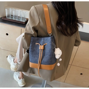 Blue denim bucket bag with brown leather trim and cute cloud charm worn by a model