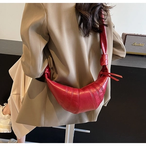 Detail of red crescent bag with litchi grain texture and knotted shoulder strap
