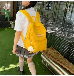 Dettaglio dello zaino giallo con ricamo Kaheiyou e ciondolo a forma di nuvola bianca