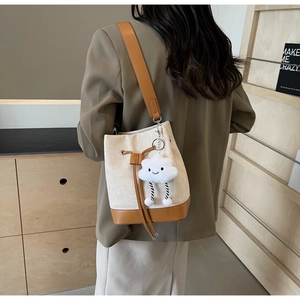 Detail of canvas bucket bag with brown leather trim and cute cloud charm on shoulder