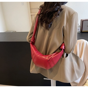 Red croissant shoulder bag shown on model featuring quilted leather and knotted wide strap