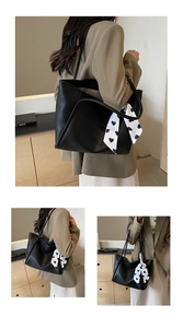 Detail of black pebbled leather tote bag featuring a decorative heart print silk scarf accessory