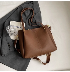 Close-up of brown lychee texture tote bag with wide strap and gold hardware