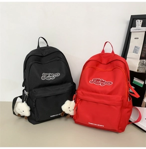 Dettaglio di zaini neri e rossi con ciondolo a nuvola di peluche bianco decorativo