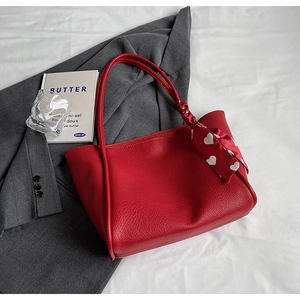 Detail of red lychee textured tote bag featuring an elegant heart print silk scarf handle