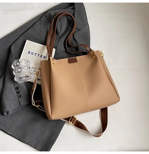 Detail of khaki faux leather tote bag with wide strap and brown logo patch for commuting