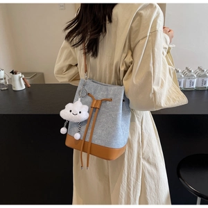 Detail view of canvas bucket bag with brown leather base and cloud charm accessory
