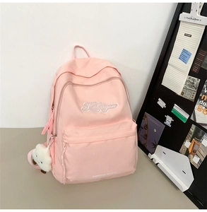 Dettaglio dello zaino rosa per studenti con ciondolo a nuvola e logo bianco ricamato