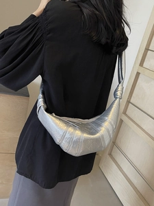 Silver metallic croissant-shaped crossbody bag with pleated texture and knotted shoulder strap