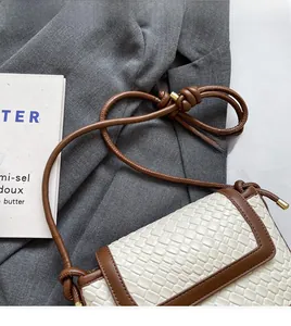 Vue détaillée du sac seau tissé blanc avec garniture en cuir marron et bandoulière nouée