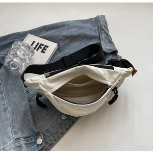 Weiße Nylon-Bauchtasche mit schwarzem Gurt und orangefarbenem Etikett auf Denim