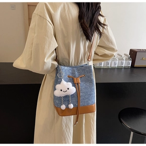 Detail of denim and leather drawstring bucket bag with a cute cloud charm accessory