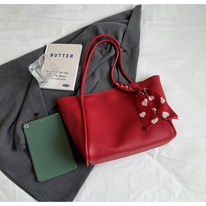 Detail of red lychee leather tote bag with decorative heart pattern scarf on handle