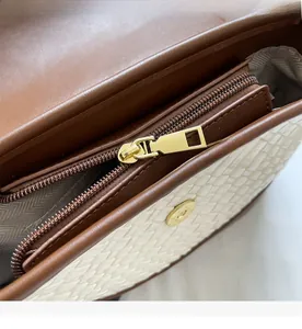 Détail de la fermeture éclair dorée et de la doublure à chevrons du sac tissé