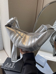Minimalist silver croissant bag with metallic pleated texture and knotted shoulder strap