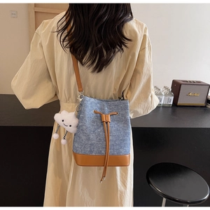 Detail of blue denim bucket bag with brown leather trim and cute white cloud charm