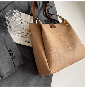 Detail of lychee pattern brown leather tote with golden buckle and V-shaped stitching