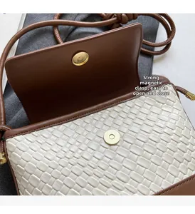 Détail de la fermeture magnétique sur le sac bandoulière tissé beige avec bordure marron