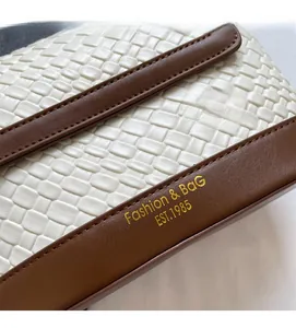 Détail du sac seau en cuir tressé blanc avec bordure marron et logo Fashion doré