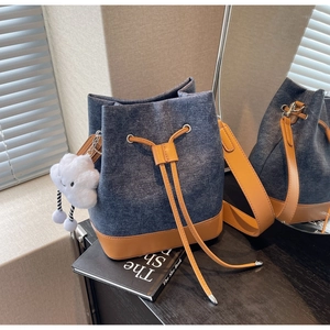 Detail of blue denim bucket bag with brown leather trim and cute white plush cloud charm