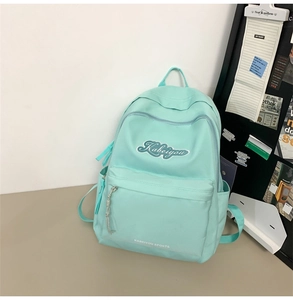 Dettaglio dello zaino in nylon verde menta con tasca con zip ed etichetta sportiva ricamata