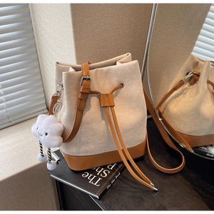 Detail of beige canvas bucket bag with brown leather trim and cute cloud charm