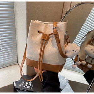 Detail of canvas bucket bag with leather trim, drawstring closure and cloud charm