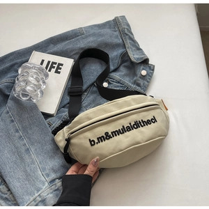 Detail der cremeweißen Bauchtasche mit schwarzer Stickerei und verstellbarem Nylongurt