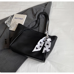 Detail of black pebbled leather tote bag featuring a heart print silk scarf on the strap