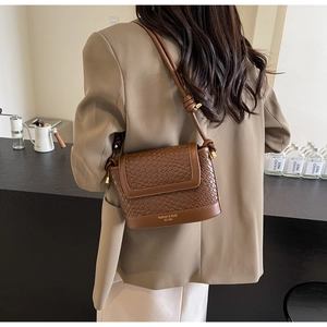 Détail d'un sac à bandoulière marron tressé avec le logo Fashion & BaG gravé sur le dessous