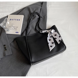 Detail of black tote bag featuring lychee texture and heart pattern silk scarf decoration