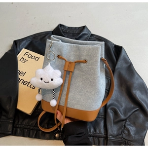 Detail of denim bucket bag with leather trim and a white plush cloud charm